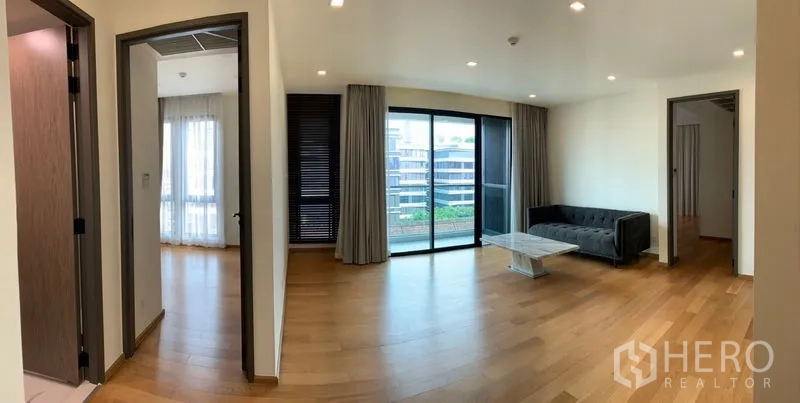 Condominium for sale in Khlong Toei, Bangkok - Open living area with balcony access and doorways leading to bedrooms.