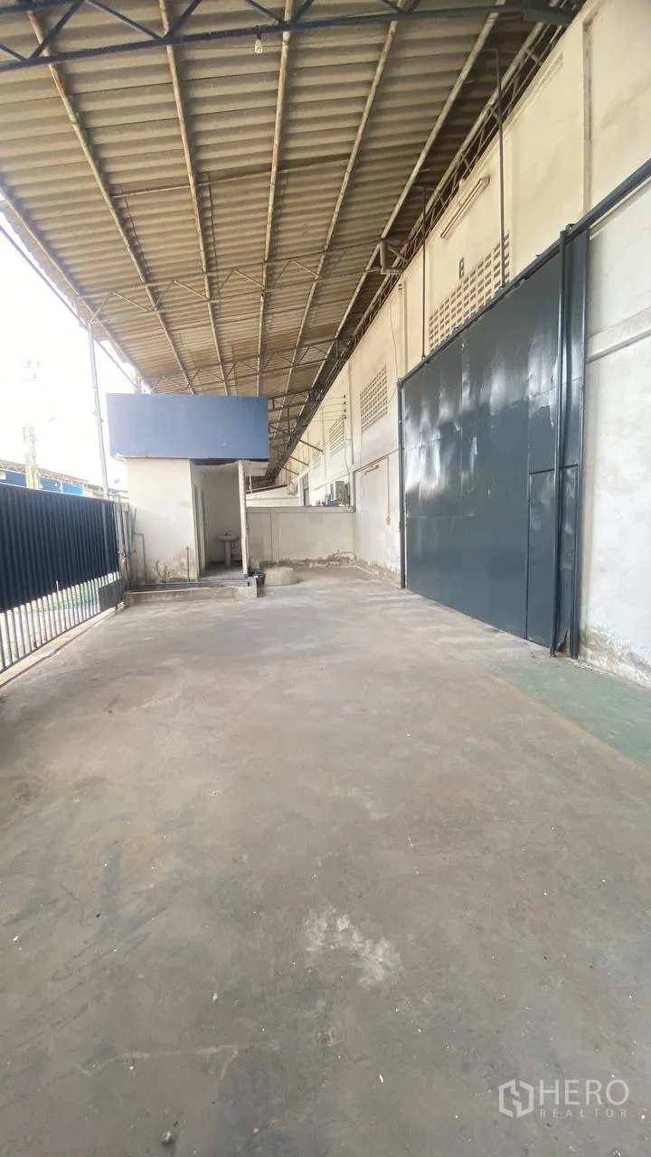 Factory for rent in Bang Phli, Samut Prakan - Long covered loading apron beside the building with wide metal doors.