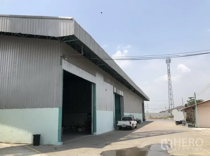 Warehouse for rent in Bang Bua Thong, Nonthaburi - Front exterior of metal-clad warehouse with wide loading bays and driveway in Bang Bua Thong.