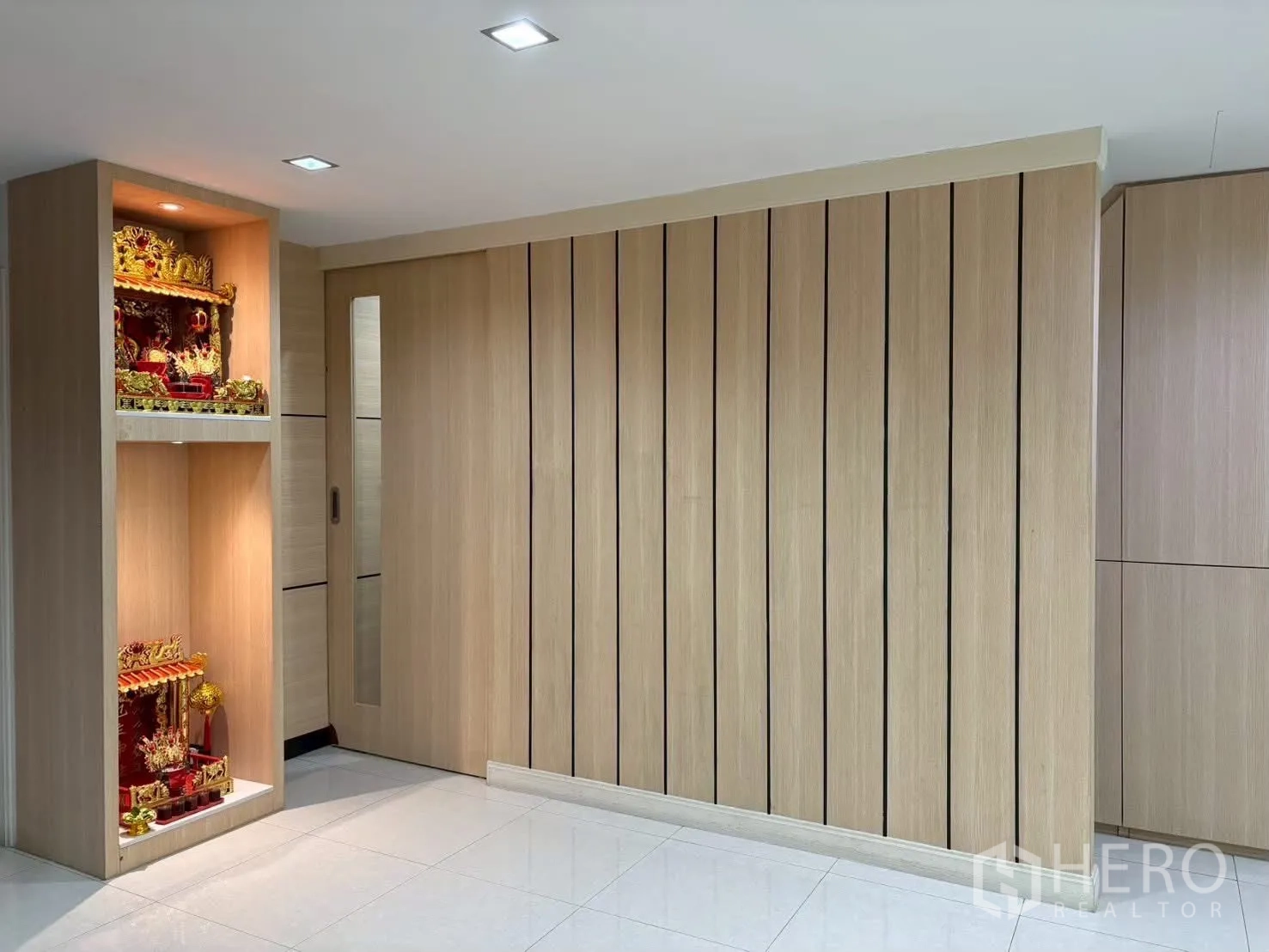 联排别墅 for rent in Pathum Wan, Bangkok - 入口区域，浅木格栅墙面与带灯神龛展示柜。