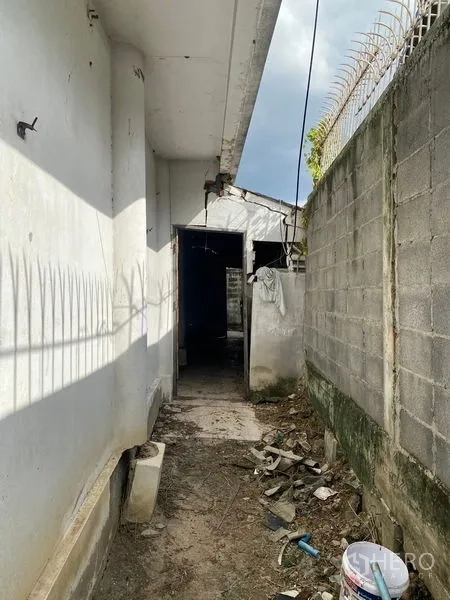 Office Space for sale in Wang Thonglang, Bangkok - Narrow side passage beside the building and boundary wall with debris on the ground.