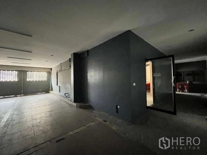 พื้นที่ขายปลีก ให้เช่าในPhaya Thai, Bangkok - โถงชั้นล่างโล่ง ผนังสีเข้ม พร้อมประตูกระจกเข้าสู่ห้องยูทิลิตี้และประตูม้วนหน้าอาคาร