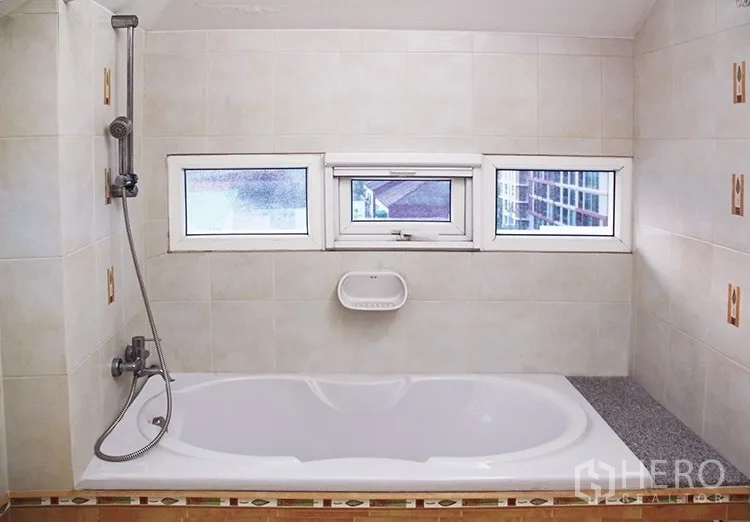 Apartment for rent in Khlong Toei, Bangkok - Bathroom with bathtub, handheld shower and three small windows