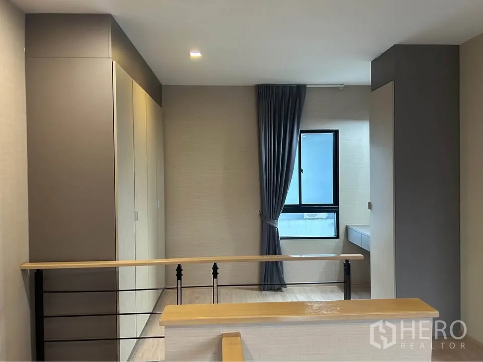 Townhouse for rent in Suan Luang, Bangkok - Upper landing with built-in wardrobes, open handrail and a window bringing in natural light.
