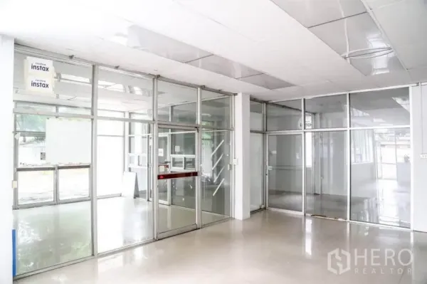 Warehouse for rent in Din Daeng, Bangkok - Glass-partitioned office area with suspended ceiling and bright tiled flooring inside the warehouse.