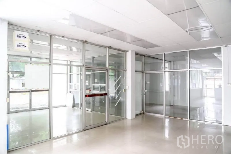 Warehouse for rent in Din Daeng, Bangkok - Glass-partitioned office area with suspended ceiling and bright tiled flooring inside the warehouse.