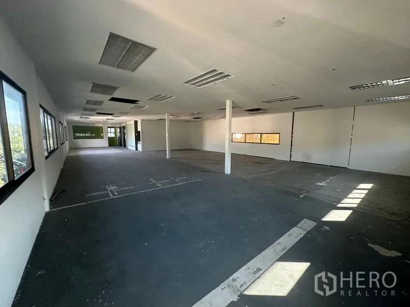 Warehouse for rent in Saphan Sung, Bangkok - Large open workspace with columns, windows and fluorescent lighting.