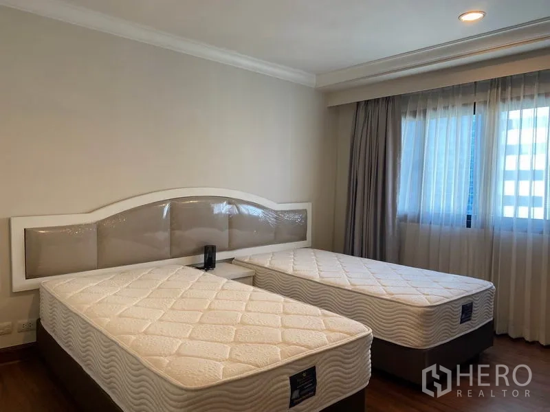 公寓 出租在Watthana, Bangkok - 明亮的双床卧室，带大窗和窗帘。