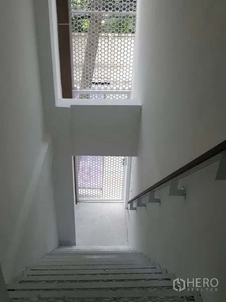 Home Office for rent in Khlong Toei, Bangkok - White stairwell with handrail and a perforated screen window facing the street.