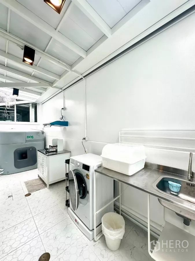 联排别墅 出租在Prawet, Bangkok - 后厨视角，燃气灶与抽油烟机、洗衣机和推拉玻璃门。