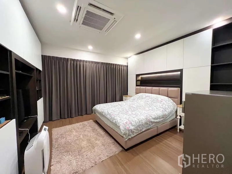 Detached House for sale in Prawet, Bangkok - Primary bedroom with king bed, built-in storage, cassette air conditioner, and blackout curtains.