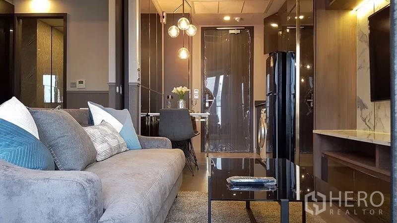 คอนโด ให้เช่าในWatthana, Bangkok - มุมมองจากโซฟาไปยังครัวขนาดกะทัดรัด ชุดทานอาหาร และโถงทางเข้าที่มีแสงอบอุ่น