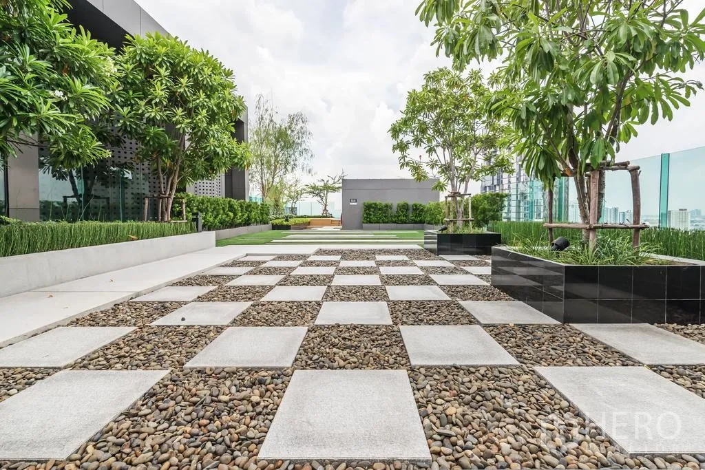 Condominium for rent in Khlong Toei, Bangkok - Rooftop garden terrace with checkerboard paving, planters and skyline views.