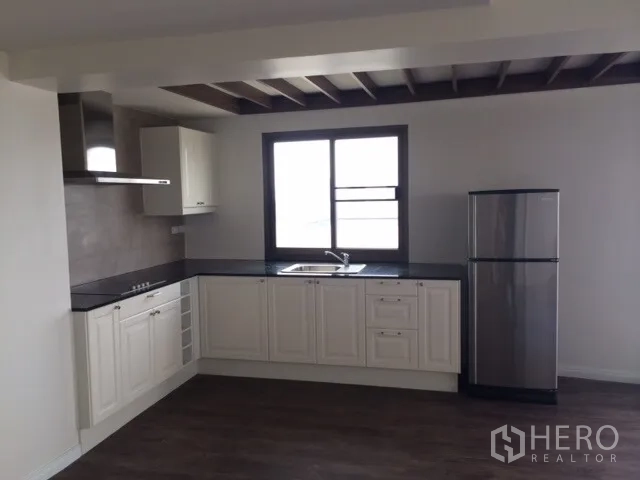 Condominium for rent or sale in Chatuchak, Bangkok - Bright L-shaped kitchen with white cabinets, dark countertops, window, and stainless-steel refrigerator.