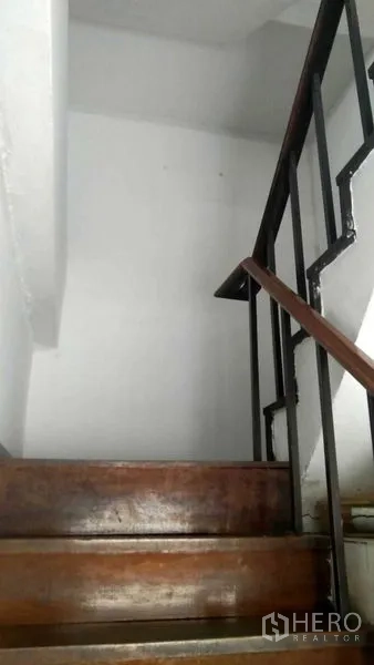 零售空间 出租在Bang Rak, Bangkok - 白色楼梯间内的木楼梯与黑色金属扶手。