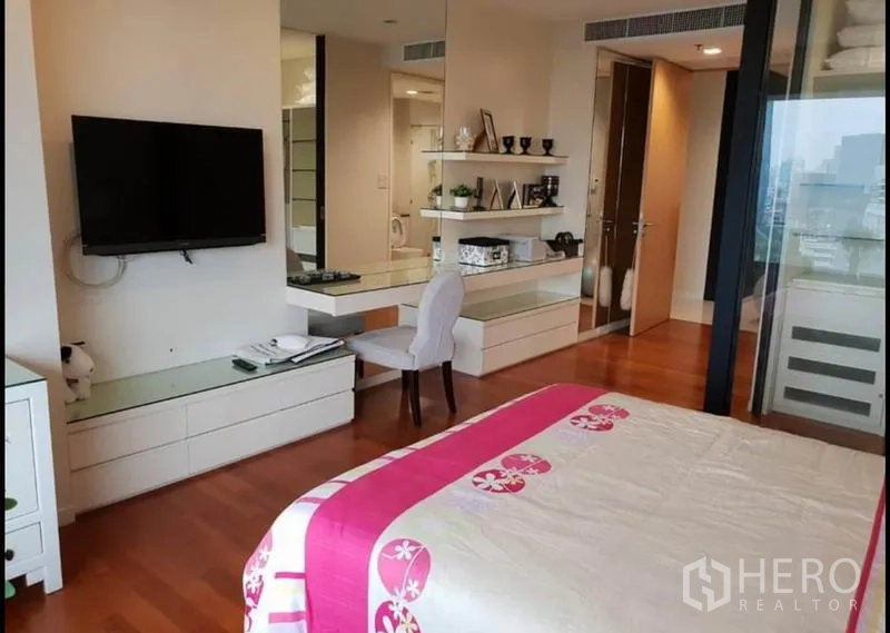公寓 出租在Sathon, Bangkok - 卧室角度，墙面电视、梳妆台、置物架及城市景观。