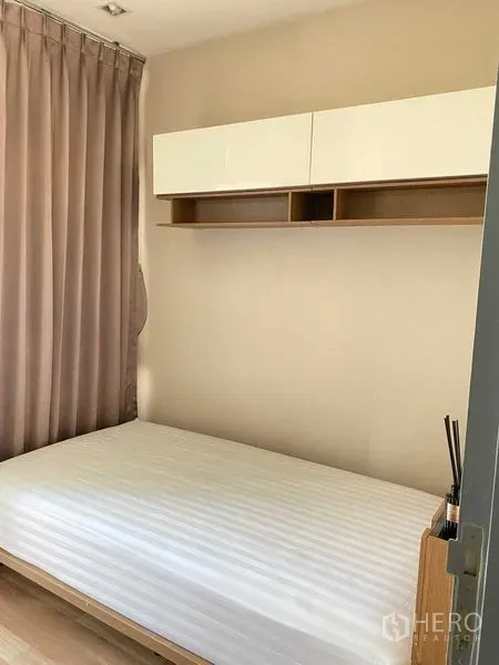 Condominium for rent in Phra Khanong, Bangkok - Cozy bedroom with platform bed, wall cabinet and floor-to-ceiling curtains.