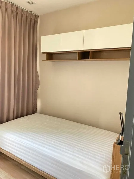 Condominium for rent in Phra Khanong, Bangkok - Cozy bedroom with platform bed, wall cabinet and floor-to-ceiling curtains.