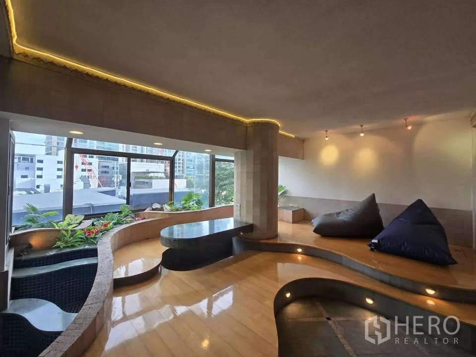 Condominium for rent in Pathum Wan, Bangkok - Sunken lounge with curved platforms, indoor planters and panoramic city windows.