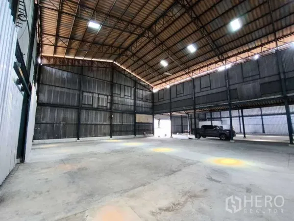 Warehouse for rent in Krathum Baen, Samut Sakhon - Open storage bay with high roof, mezzanine walkway, and large entry suitable for truck loading.