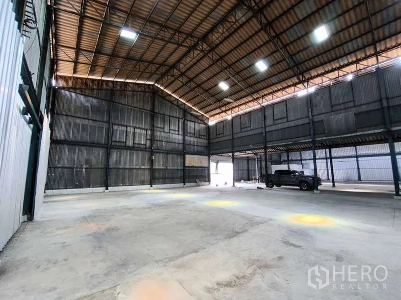 Warehouse for rent in Krathum Baen, Samut Sakhon - Open storage bay with high roof, mezzanine walkway, and large entry suitable for truck loading.