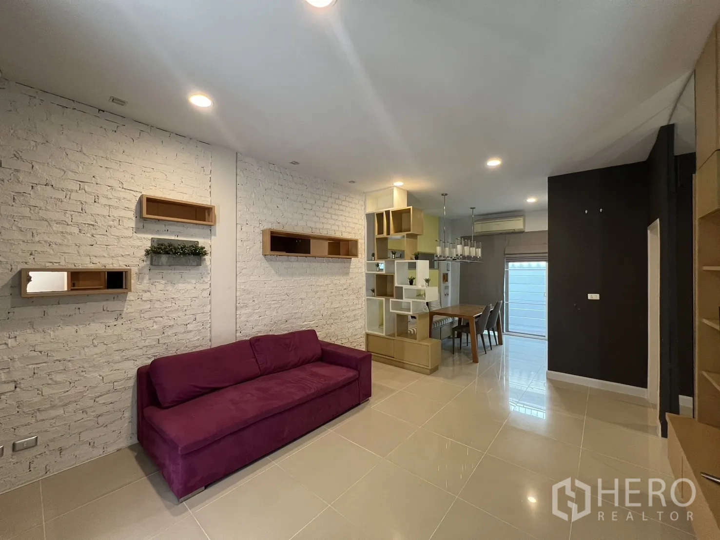 Townhouse for rent in Wang Thonglang, Bangkok - Living area with white brick feature wall, display shelves and dining set.