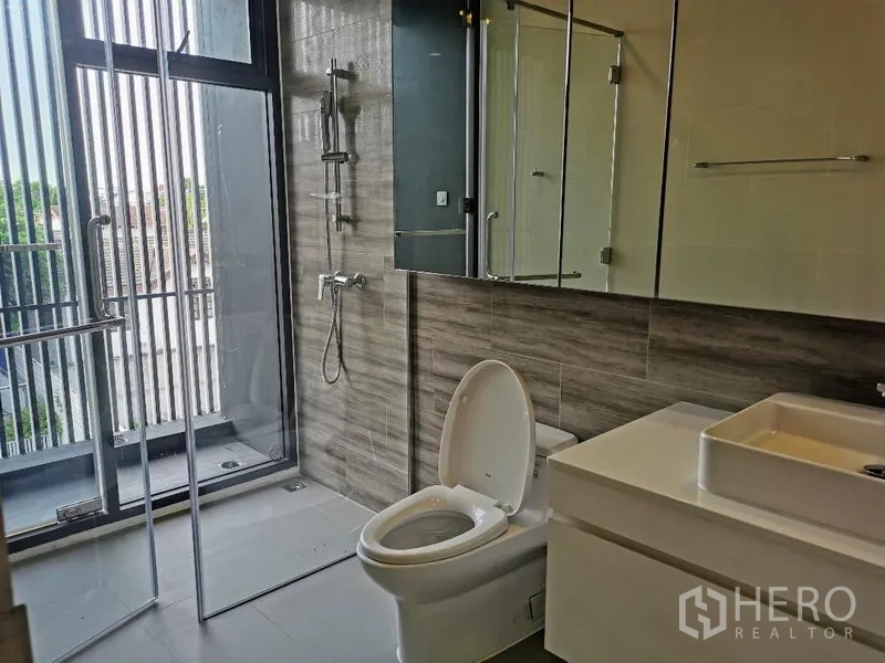 Detached House for sale in Wang Thonglang, Bangkok - Contemporary bathroom with glass shower and a door to the balcony for natural light.