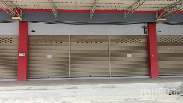 Shophouse for rent in Thon Buri, Bangkok - Close-up of the ground-floor shopfront with beige roller shutters and a covered walkway.