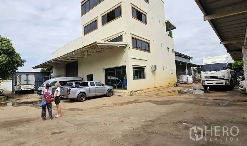 Warehouse for rent in Bang Kruai, Nonthaburi - Large yard and loading area with office building and trucks on site.