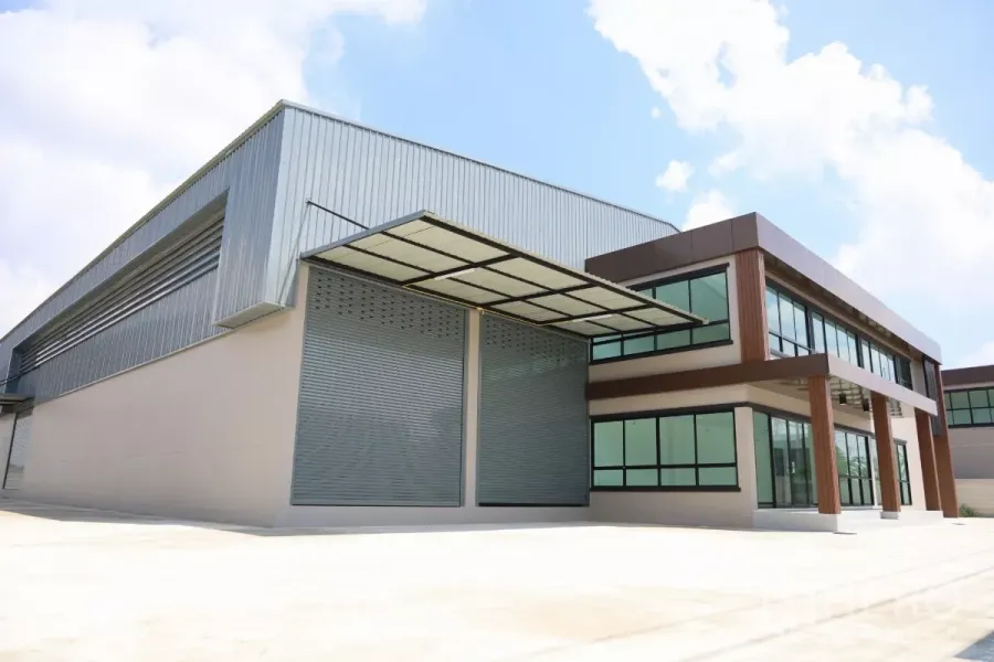 Factory for rent or sale in Bang Len, Nakhon Pathom - Front view of a newly built factory in Bang Len with large roller shutter doors, a two-storey glass-fronted office and a covered loading canopy.