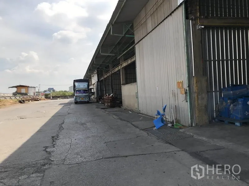 货栈 出租在Mueang Pathum Thani, Pathum Thani - 仓库外部装卸区，卡车可直接进出，配高大的金属推拉门。