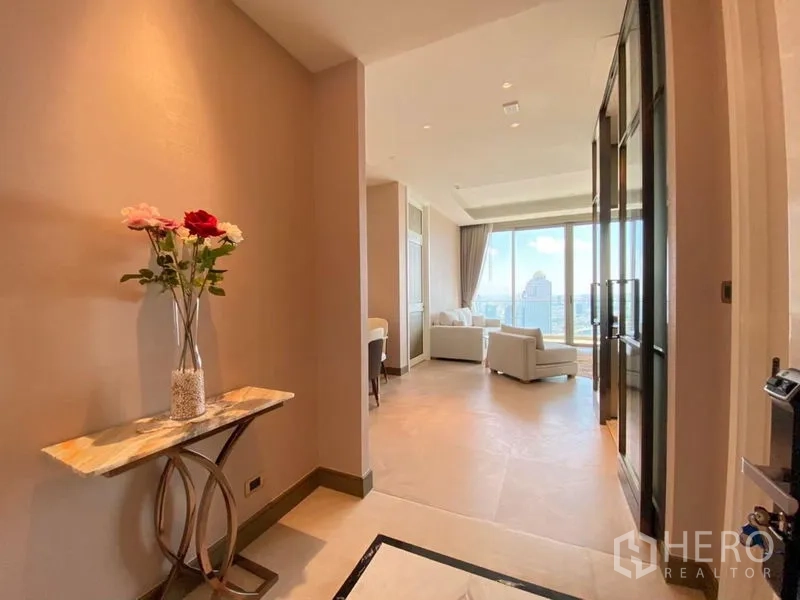 Condominium for rent in Khlong San, Bangkok - Bright entry hall with a marble console and flowers leading to a living room with floor‑to‑ceiling windows and city view.