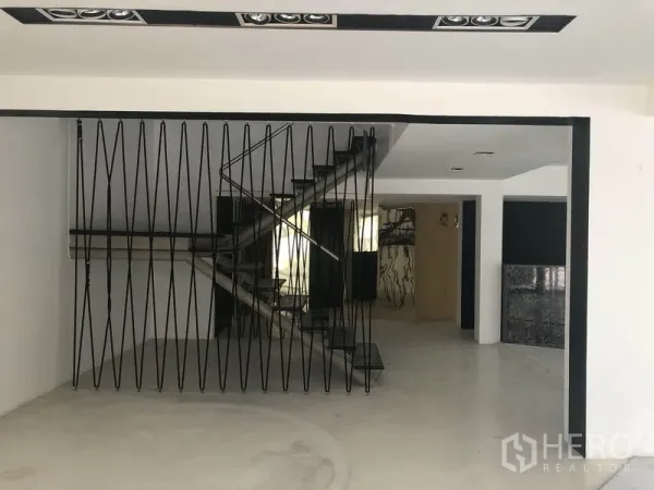 零售空间 出租在Watthana, Bangkok - 开放式零售室内，黑色金属楼梯与几何隔断，白墙与亮面地坪。