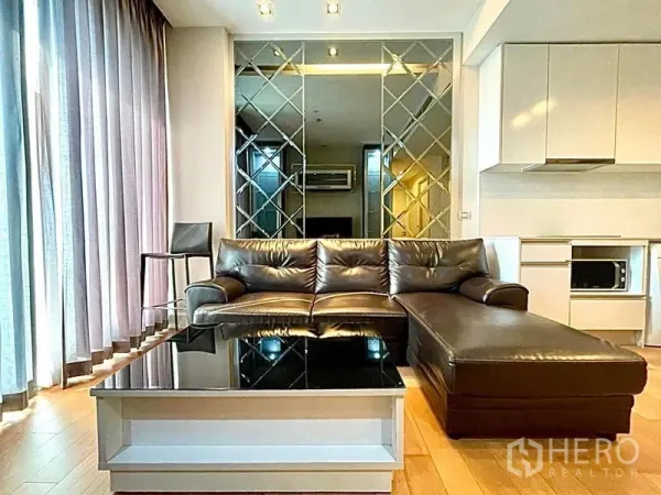 คอนโด ให้เช่าในChatuchak, Bangkok - ห้องนั่งเล่นสว่าง โซฟาหนังตัวแอล ผนังกระจกตกแต่ง และผ้าม่านสูงจรดเพดาน
