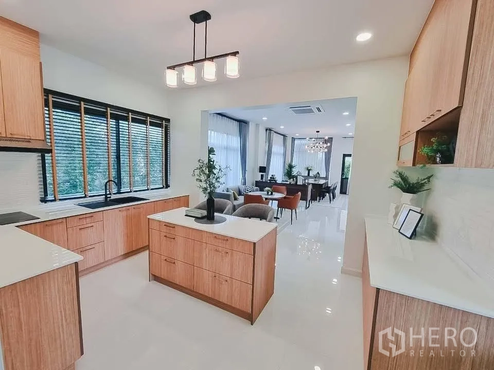 Detached House for rent or sale in Bang Phli, Samut Prakan - Contemporary kitchen with island, wood cabinetry, and view to dining and living area.