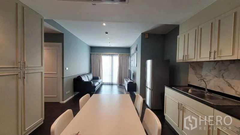 คอนโด ให้เช่าในKhlong Toei, Bangkok - มุมมองจากครัวสู่ห้องนั่งเล่น มีโซฟา ตู้บิวท์อิน และประตูกระจกระเบียงรับแสงธรรมชาติ