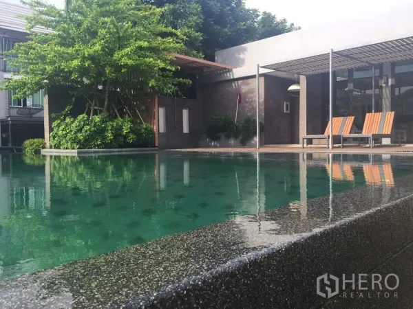 ทาวน์เฮาส์ ให้เช่าหรือขายในLat Phrao, Bangkok - สระว่ายน้ำส่วนกลางพร้อมเก้าอี้อาบแดด พื้นที่นั่งพักผ่อนใต้ร่ม และต้นไม้ร่มรื่นข้างคลับเฮาส์