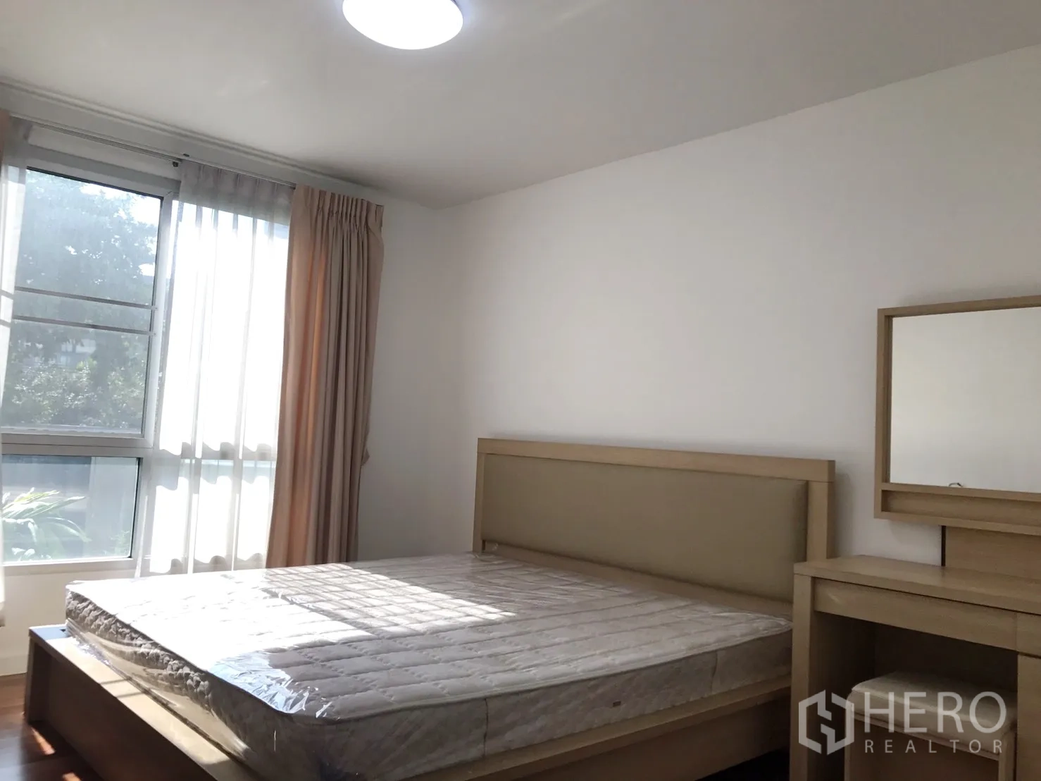 Condominium for rent in Watthana, Bangkok - Sunlit bedroom with a large window, double bed and dressing table.