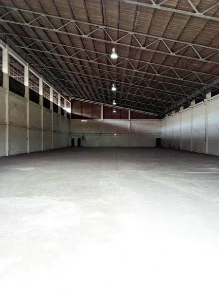 Warehouse for rent in Khlong Toei, Bangkok - Spacious warehouse interior with a high steel truss roof, concrete floor, and overhead lighting.