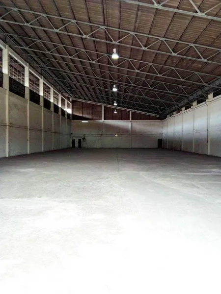 Warehouse for rent in Khlong Toei, Bangkok - Spacious warehouse interior with a high steel truss roof, concrete floor, and overhead lighting.
