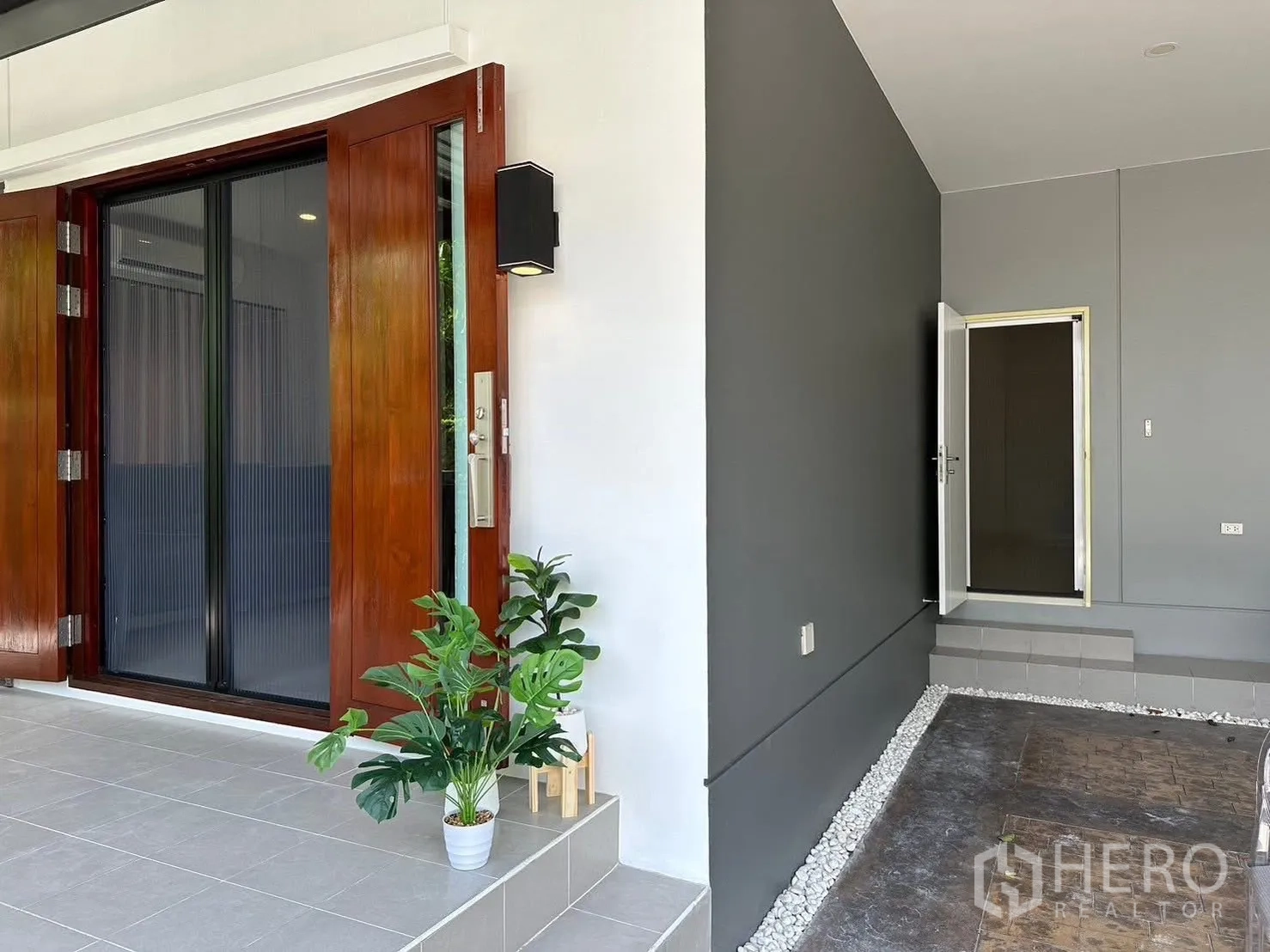 独栋房屋 for rent in Bang Phli, Samut Prakan - 入户门廊设木质推拉门、灰色墙面与盆栽。
