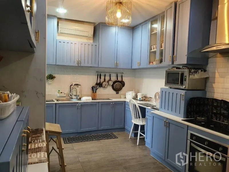 บ้าน ขายในLam Luk Ka, Pathum Thani - ห้องครัวบิวท์อินโทนสีฟ้า กระเบื้องซับเวย์ เตาแก๊ส เครื่องดูดควัน และโคมไฟแขวน.