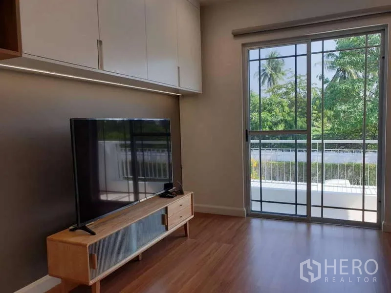 บ้าน ให้เช่าในSathon, Bangkok - มุมนั่งเล่นพร้อมชั้นวางทีวี และประตูกระจกบานเลื่อนเปิดสู่ระเบียงวิวต้นไม้