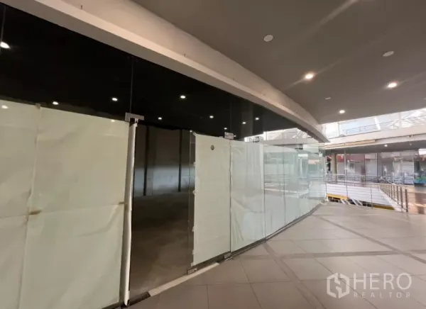 零售空间 出租 - 商场二楼弧形玻璃门面的零售铺位，临室内走道与天花灯光。