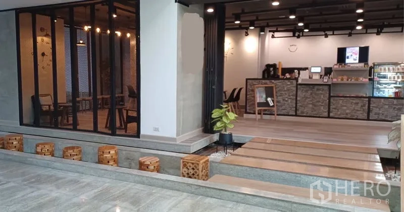 零售空间 出租在Khlong Toei, Bangkok - 开放式商铺空间，吧台收银区、台阶式步道、绿植与黑色轨道射灯。