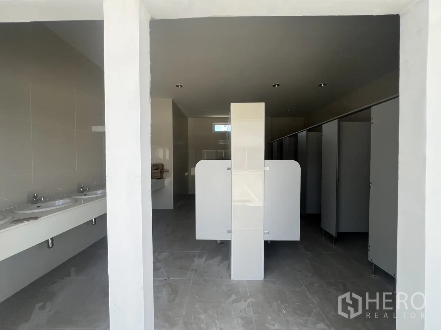 Warehouse for rent in Min Buri, Bangkok - Entrance view of restrooms with partitions, sinks, and tiled flooring.