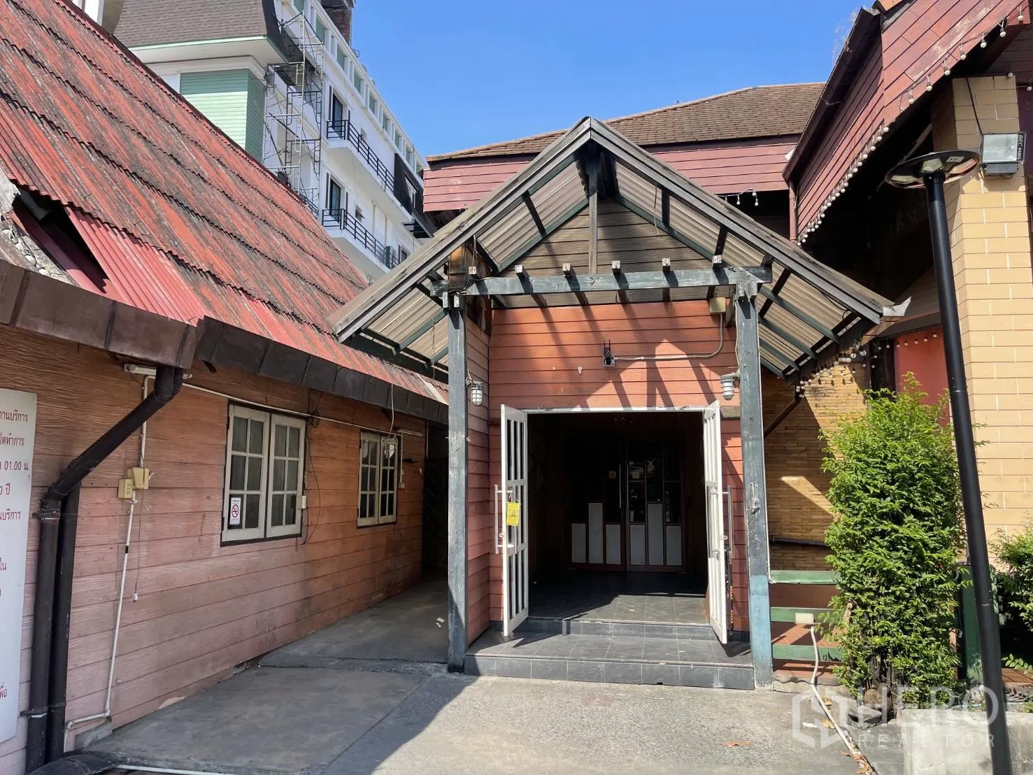 พื้นที่ขายปลีก ให้เช่าในSuan Luang, Bangkok - ภาพระยะใกล้ของทางเข้าอาคารหลัก มีหลังคากันสาด ประตูกระจก และผนังไม้
