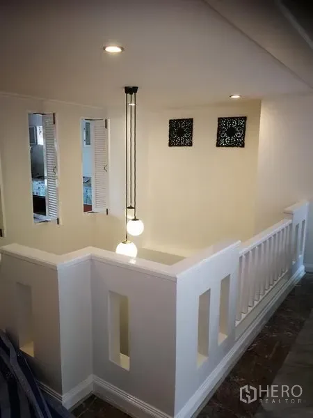 Townhouse for rent or sale in Watthana, Bangkok - Stair landing with white balustrade and modern pendant lighting.