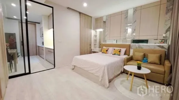 คอนโด ขายในPathum Wan, Bangkok - ห้องคอนโดสตูดิโอสว่าง พร้อมเตียง โซฟา ผนังลายหินอ่อน และประตูกระจกบานเลื่อนไปครัว