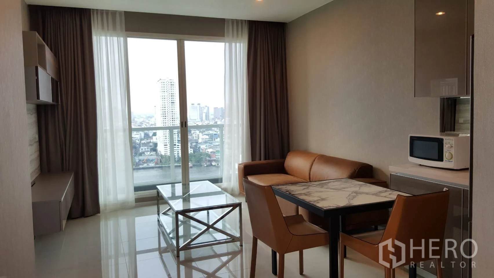 Condominium for rent in Bang Kho Laem, Bangkok - Bright living and dining area with leather sofa, marble-top table, glass coffee table and floor-to-ceiling windows overlooking the Chao Phraya River in a Bang Kho Laem condo.